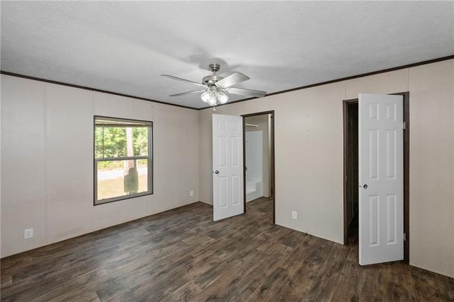 Unfurnished bedroom featuring dark wood-style flooring, a ceiling fan, and crown molding | Image 21