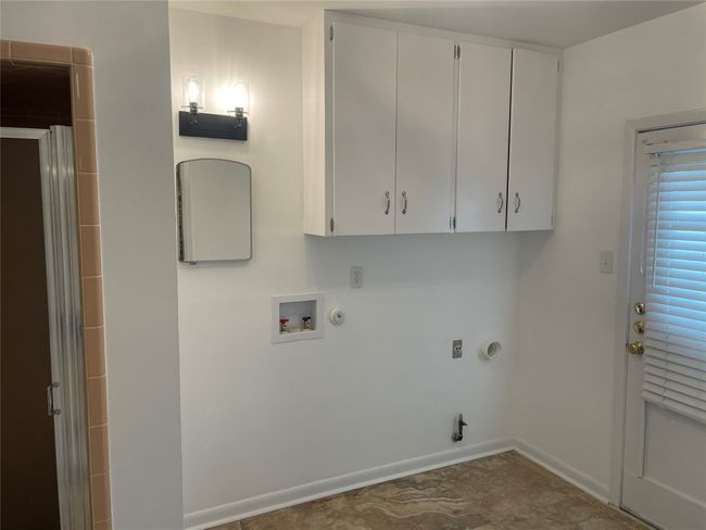 Washroom featuring shower, hookup for a gas dryer, hookup for a washing machine, and cabinet space | Image 6