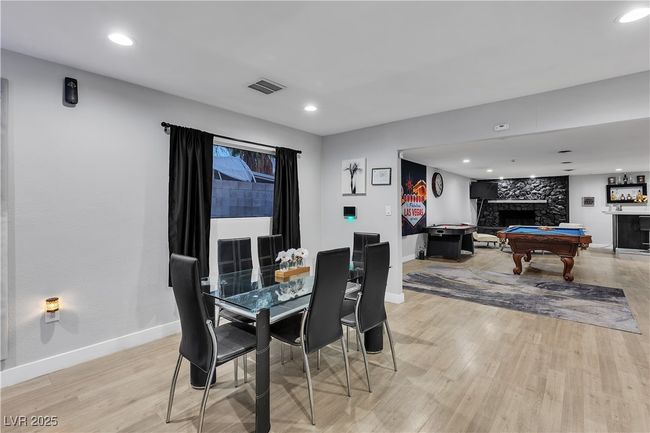 Dining area with visible vents, baseboards, light wood finished floors, a fireplace, and billiards | Image 8