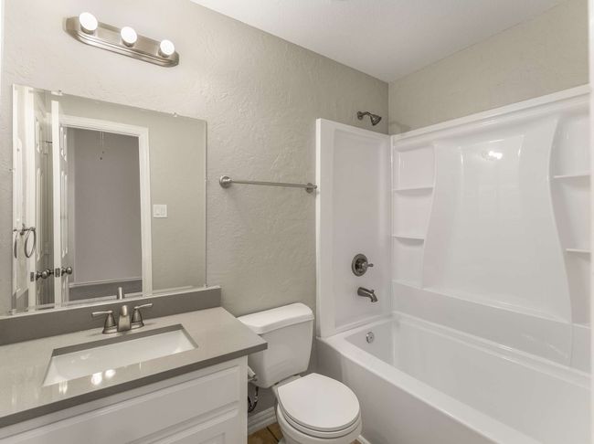 Full bathroom featuring washtub / shower combination, toilet, vanity, and a textured wall | Image 31