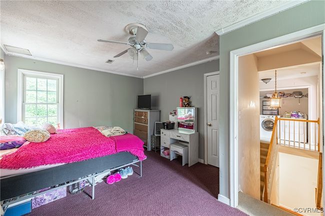 Carpeted bedroom featuring a textured ceiling, ornamental molding, ceiling fan, and washer / dryer | Image 11