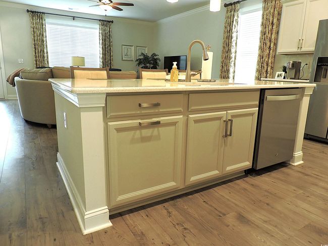 Kitchen featuring appliances with stainless steel finishes, crown molding, open floor plan, light wood-type flooring, and a sink | Image 8