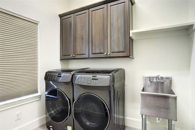 Clothes washing area with washing machine and dryer, baseboards, a sink, and cabinet space | Image 24