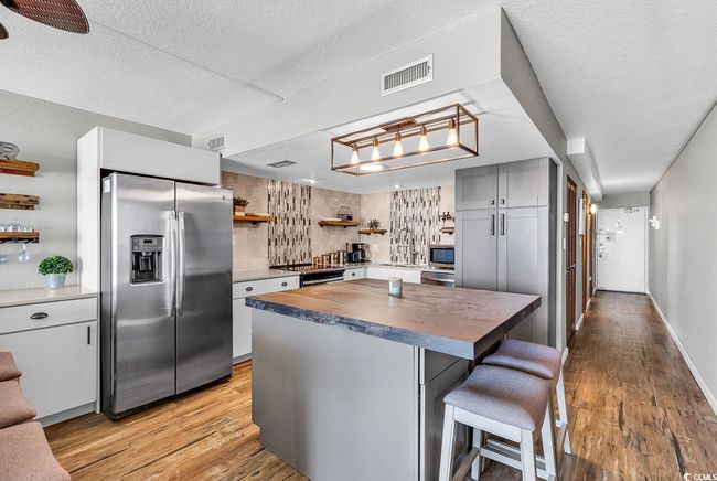 Kitchen with open shelves, light wood-style flooring, stainless steel appliances, visible vents, and wood counters | Image 16