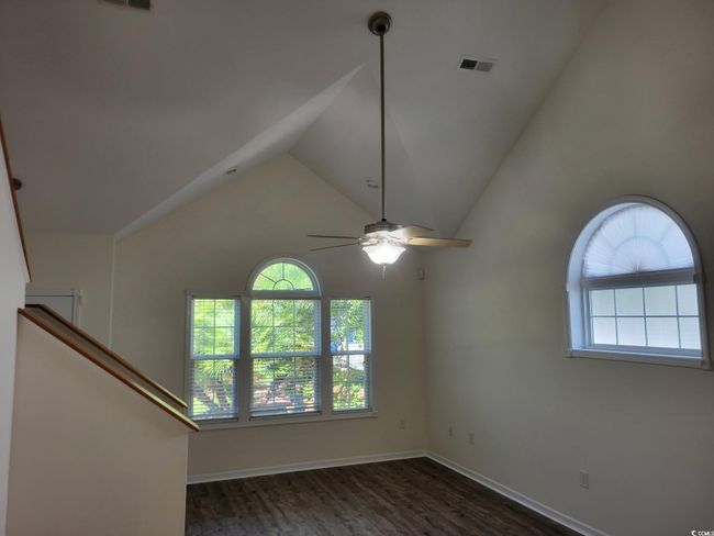 Empty room with wood finished floors, a ceiling fan, and high vaulted ceiling | Image 4