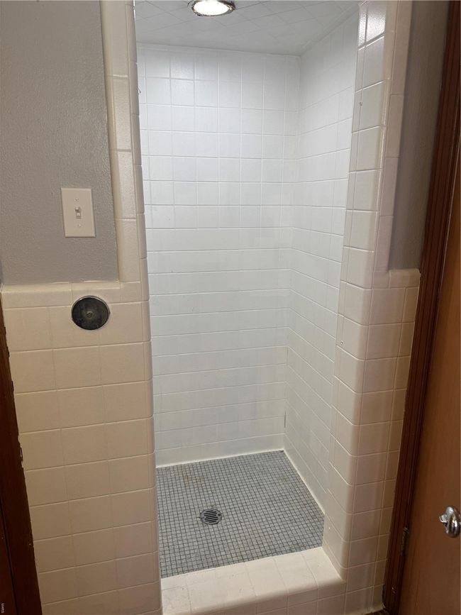 Full bathroom featuring a wainscoted wall, tiled shower, and tile walls | Image 7