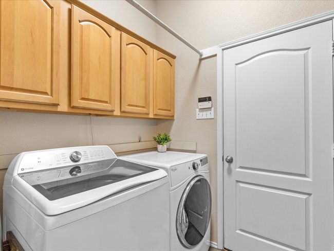 Washroom featuring washing machine and dryer, cabinet space, and a textured wall | Image 15