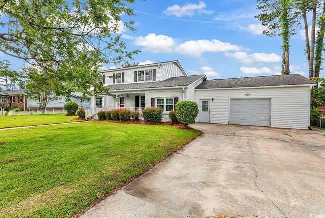 Traditional home featuring a garage, a porch, concrete driveway, and roof with shingles | Image 33