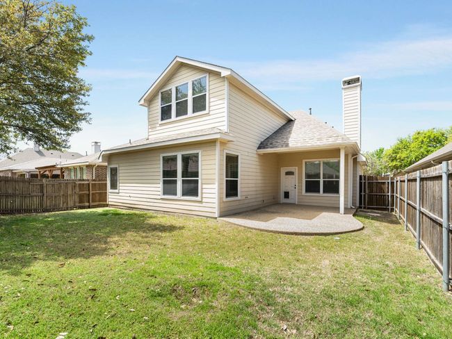 Back of house with a fenced backyard, a chimney, a patio area, and roof with shingles | Image 38