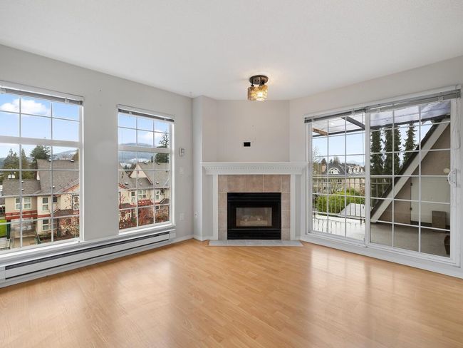 Unfurnished living room with baseboards, a baseboard heating unit, a tiled fireplace, and light wood-type flooring | Image 6