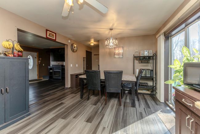 Dining area featuring ceiling fan with notable chandelier and wood finished floors | Image 9