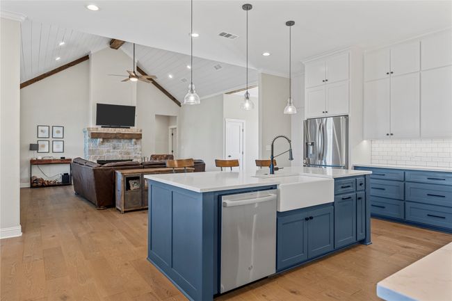 Kitchen featuring white cabinetry, visible vents, blue cabinets, a sink, and stainless steel appliances | Image 9
