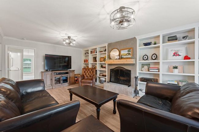 Spacious living room featuring a cozy fireplace and built-in shelves, creating a warm and inviting atmosphere. | Image 8