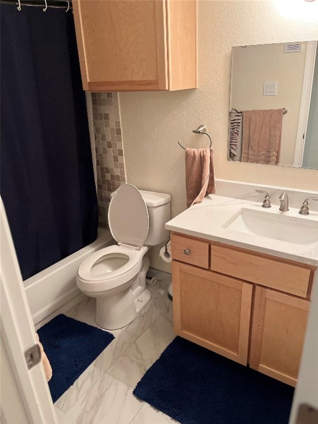 Full bath with marble finish flooring, vanity, shower / bath combo with shower curtain, and a textured wall | Image 20