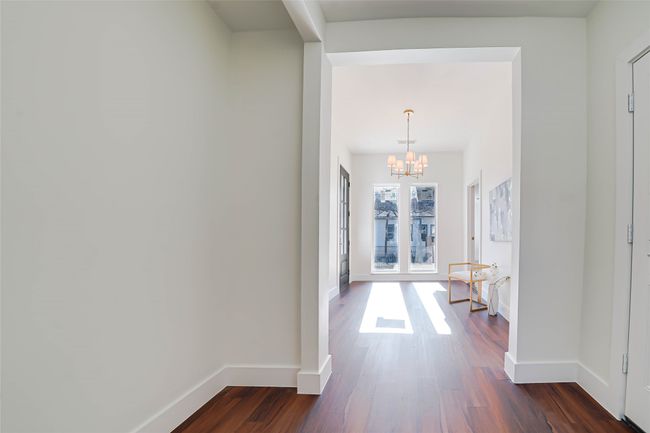Hallway with dark wood-type flooring and a chandelier | Image 16