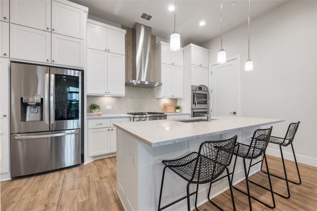 Elegant chef's kitchen with center island, Thermador gas stove, double oven, built in Jenn Air microwave, under cabinet lighting, wine fridge, and pantry. | Image 10