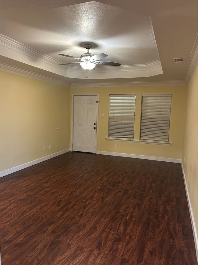Spare room featuring crown molding, a raised ceiling, dark wood finished floors, ceiling fan, and a textured ceiling | Image 8