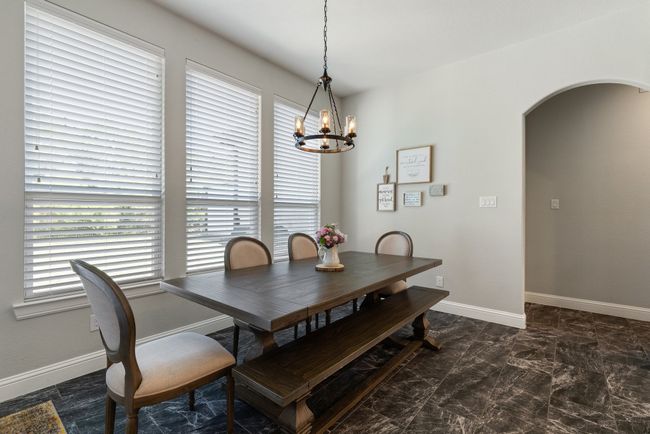 Dining space with arched walkways, marble finish floor, baseboards, and an inviting chandelier | Image 14