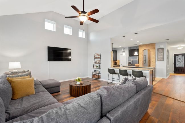 Living area with arched walkways, a ceiling fan, wood-type flooring, and high vaulted ceiling | Image 13