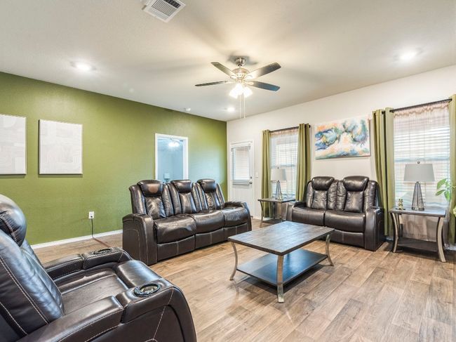 Living room with light wood-type flooring, baseboards, ceiling fan, and visible vents | Image 13