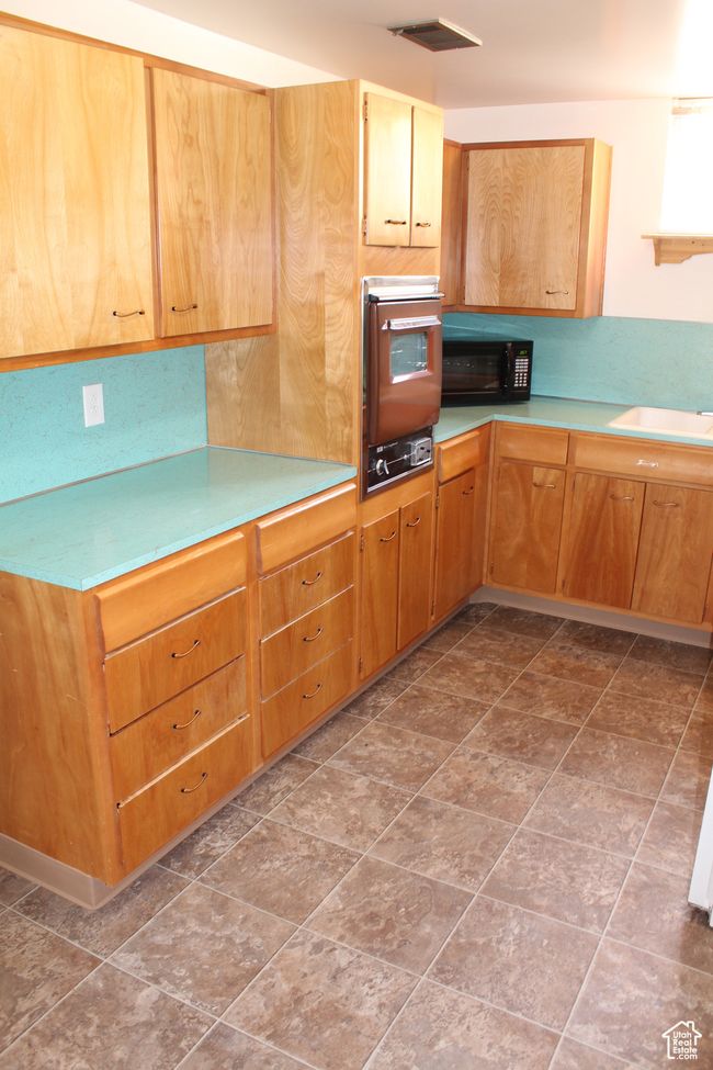 Kitchen with oven, light countertops, and black microwave | Image 17