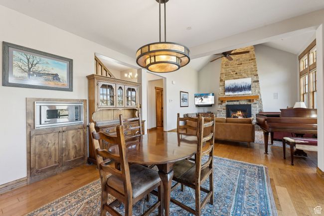 Dining space featuring ceiling fan, vaulted ceiling, light wood-type flooring, and a stone fireplace | Image 14
