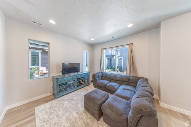 Living room with wood finished floors, baseboards, recessed lighting, and a textured ceiling | Image 8
