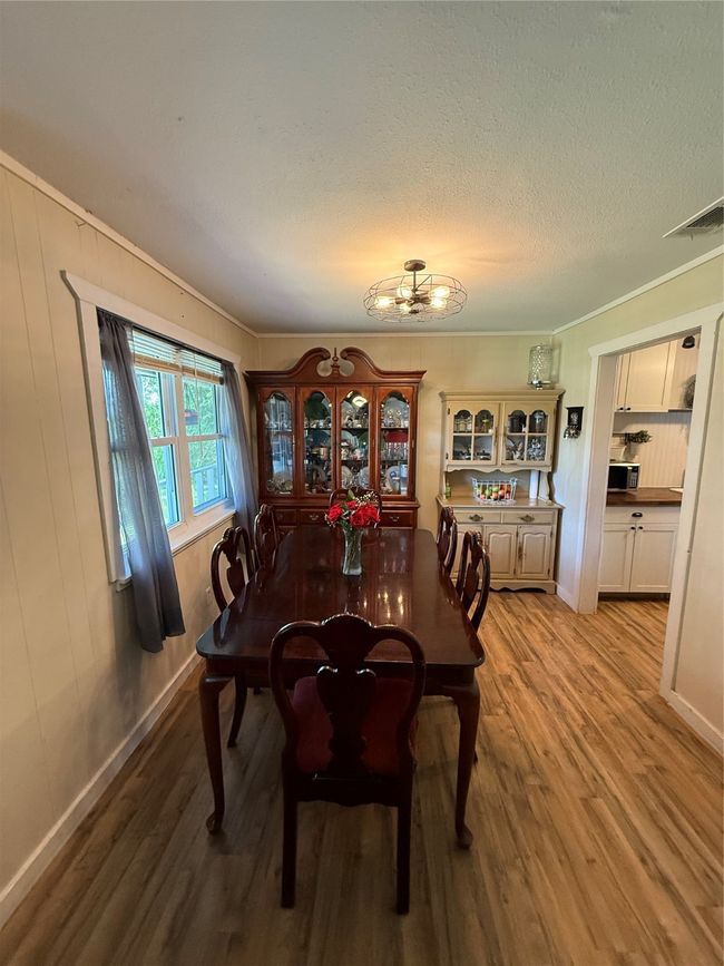 Dining area featuring light wood-style floors, a chandelier, ornamental molding, wooden walls, and a textured ceiling | Image 13