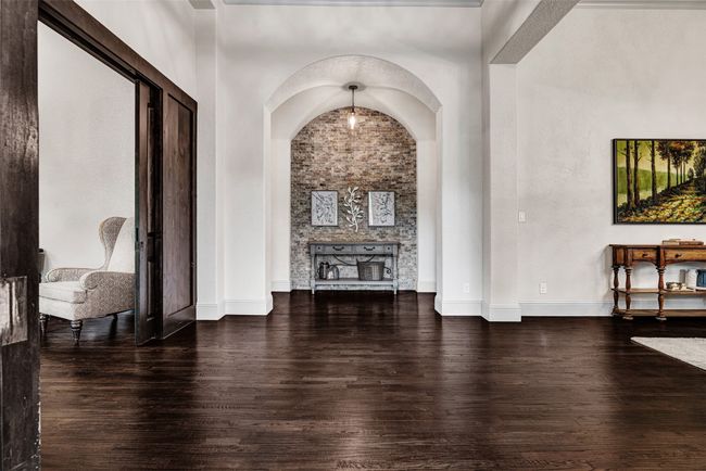 Step past the front door to be greeted by the formal dining room, executive home office and a wonderful stone accent wall framed by arched doorways. | Image 15