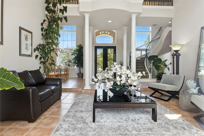 Tiled living room with decorative columns, a towering ceiling, and stairway | Image 6