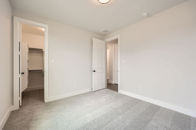 Unfurnished bedroom with a closet, carpet flooring, a walk in closet, baseboards, and visible vents | Image 20