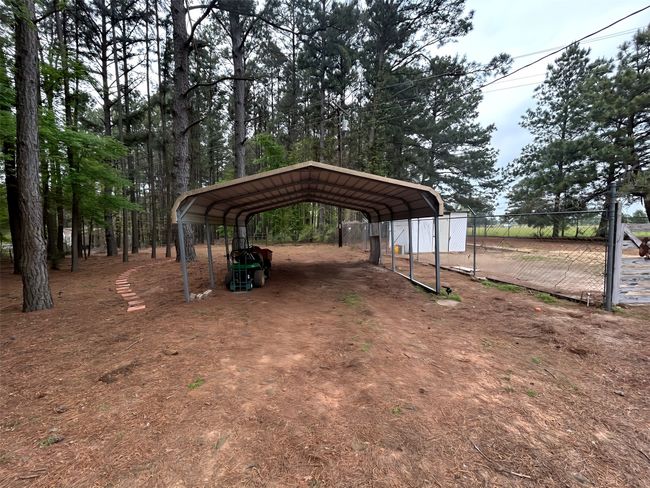 View of yard with a detached carport, fence, and dirt driveway | Image 35