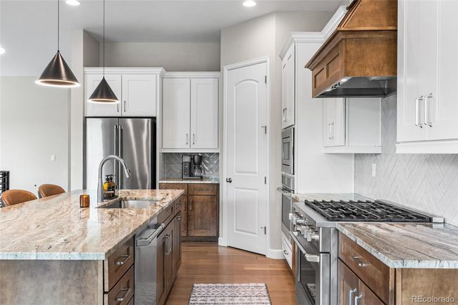 Chef's dream kitchen with upgraded pendant lighting, GE Cafe appliances (6-burner gas range, wall oven/airfryer, French door refrigerator) custom range hood and herringbone tile backsplash. Large granite island soft-close maple cabinets will roll-out drawers and large pantry. | Image 13