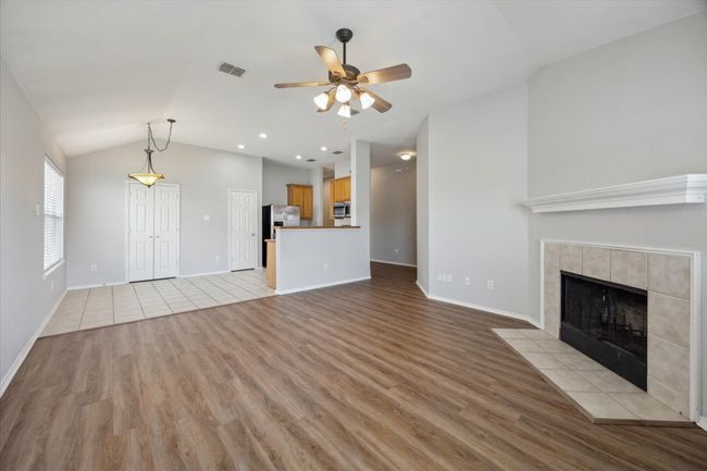 Unfurnished living room featuring light wood-style flooring, a ceiling fan, vaulted ceiling, a tile fireplace, and baseboards | Image 8
