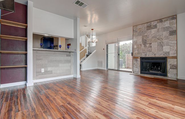 Unfurnished living room featuring visible vents, a large fireplace, and wood finished floors | Image 4