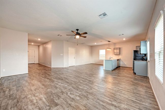 Unfurnished living room featuring a ceiling fan, wood finished floors, baseboards, and recessed lighting | Image 7