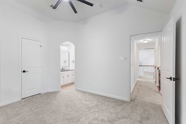 Unfurnished bedroom with arched walkways, ensuite bath, light colored carpet, visible vents, and lofted ceiling | Image 36