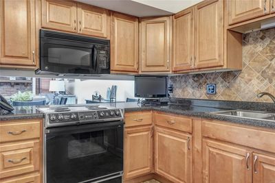 Kitchen features plenty of beautiful cabinets, lots of counter space, and an interesting pass-through to the dining room space. | Image 2