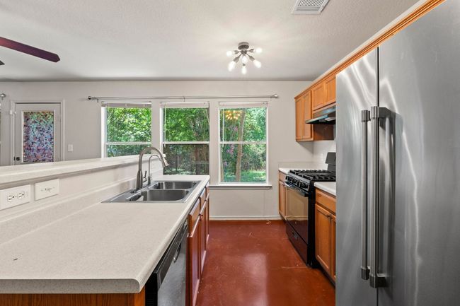 A stainless steel fridge and a gas cooktop grace the kitchen. | Image 11