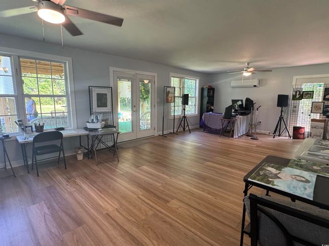 Living area featuring ceiling fan, french doors, an office area, an AC wall unit, and light wood-type flooring | Image 17