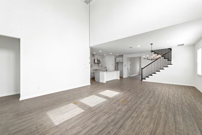 Unfurnished living room with stairway, wood finished floors, baseboards, recessed lighting, and a chandelier | Image 7