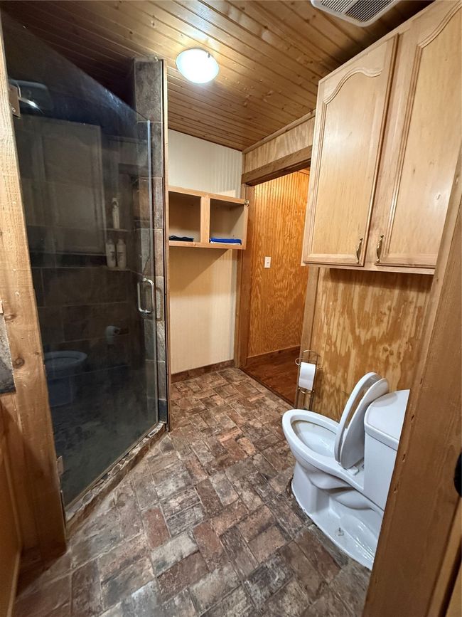 Full bathroom with toilet, a shower stall, wood ceiling, and baseboards | Image 11