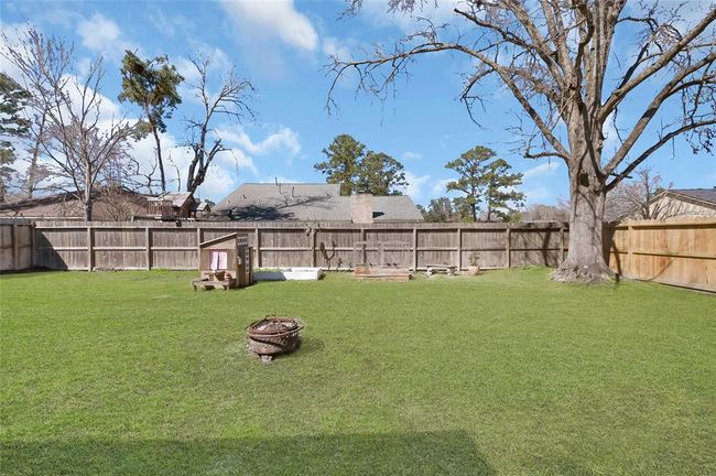 Spacious backyard with lush green grass, mature trees, and a wooden fence for privacy. Great space for family activities and relaxation. | Image 25