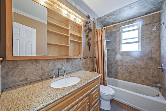 Bathroom featuring vanity, shower / tub combo, toilet, decorative backsplash, and tile patterned floors | Image 23