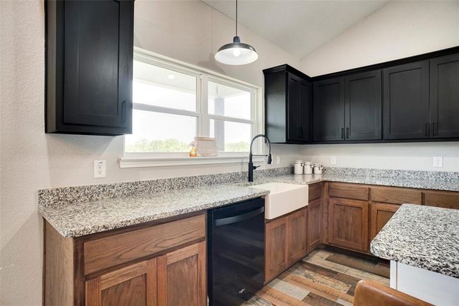 Kitchen with vaulted ceiling, hanging light fixtures, hardwood / wood-style flooring, black dishwasher, and sink | Image 15