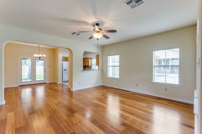 Unfurnished living room with arched walkways, ceiling fan, a chandelier, and light wood-style flooring | Image 8