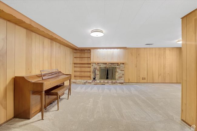 Living room featuring light carpet, wooden walls, and a brick fireplace | Image 29