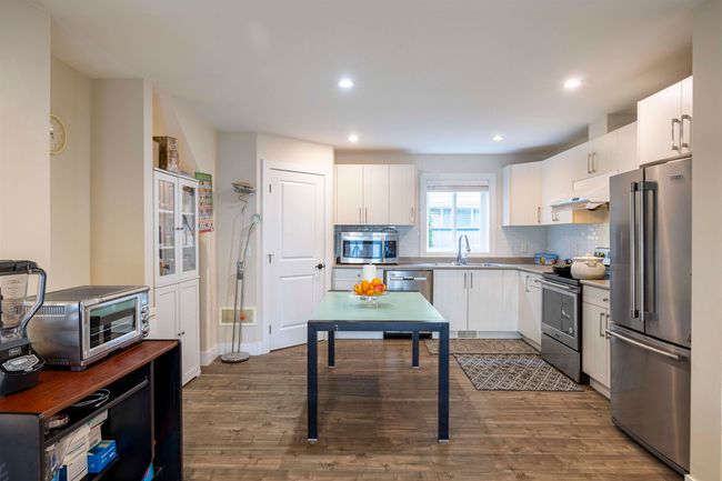 Kitchen with dark wood finished floors, a sink, decorative backsplash, stainless steel appliances, and under cabinet range hood | Image 8