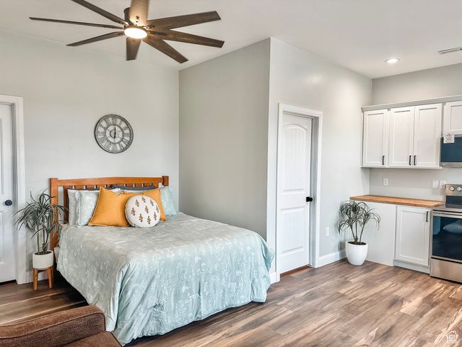 Bedroom featuring a ceiling fan, wood finished floors, baseboards, visible vents, and recessed lighting | Image 29