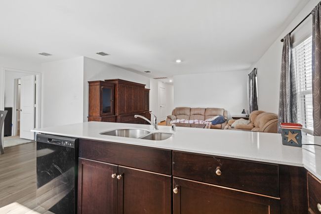 Kitchen with light countertops, visible vents, a sink, and black dishwasher | Image 6